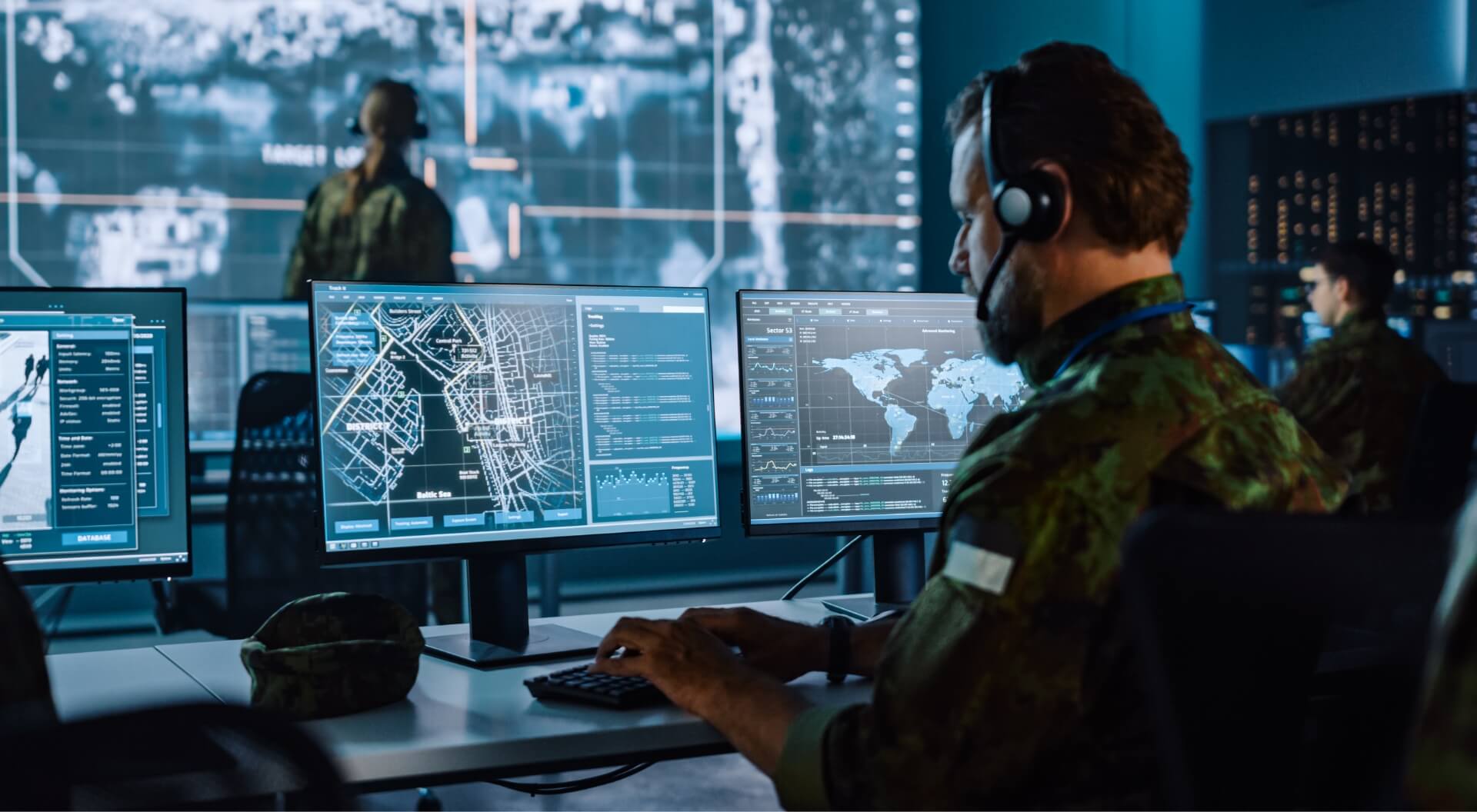 military personnel working in a command center with dashboards and maps displayed on screens