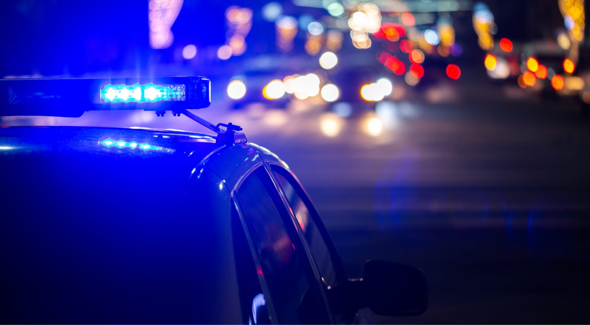 Slightly blurred image of part of a police vehicle with sirens on at night